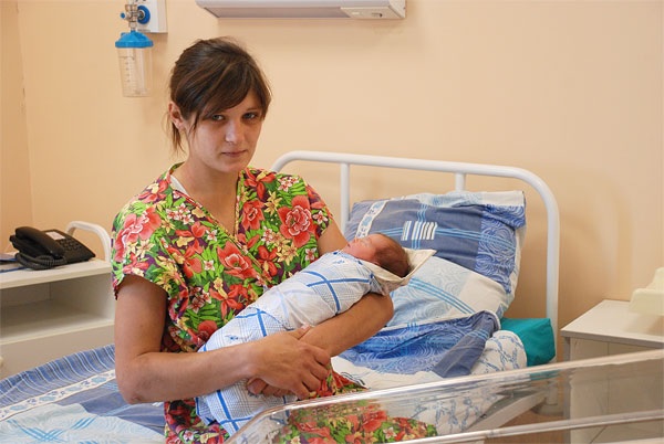 Мать держит новорожденную в роддоме